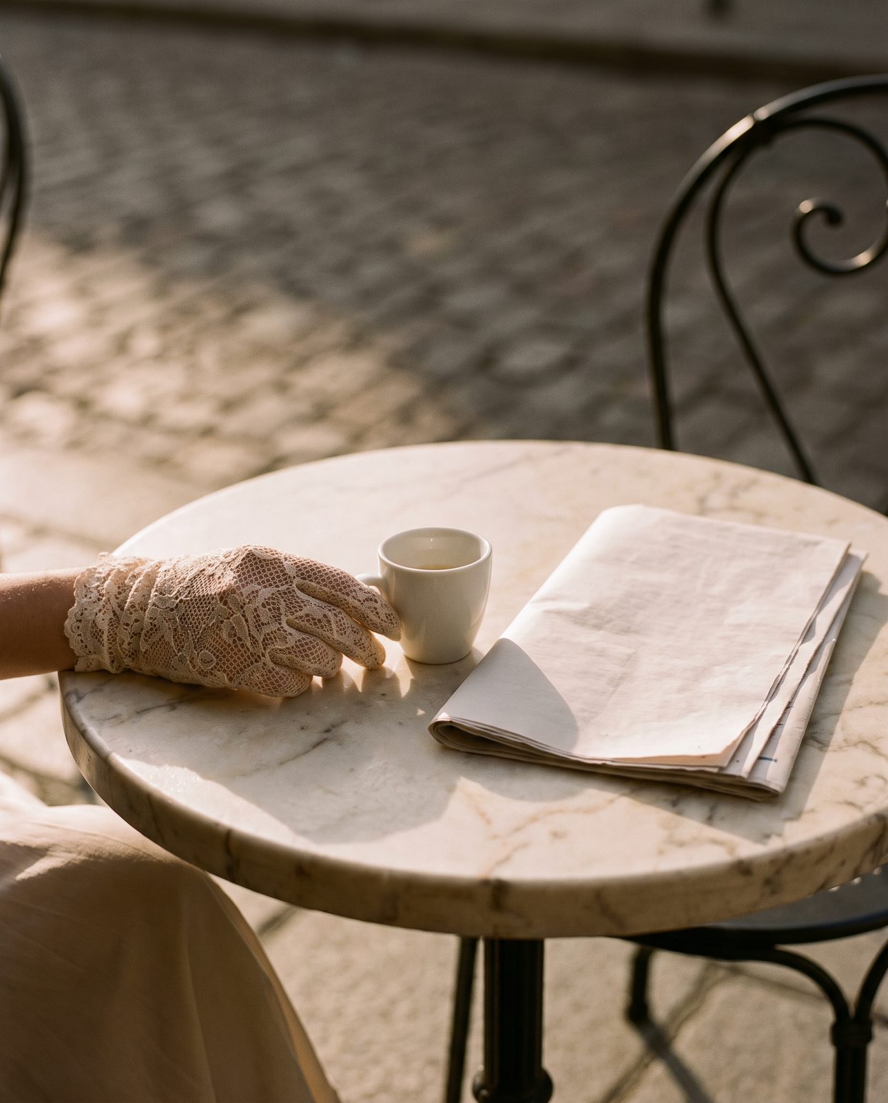 An espresso and a gloved hand on a marble café table